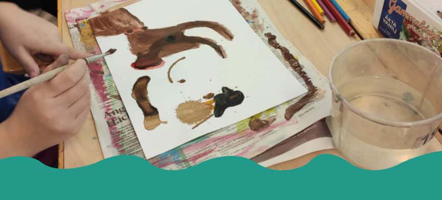 Närbild elev målar på papper med kaffefläckar på.