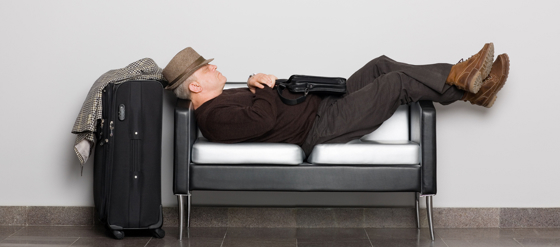 Dekorbild på man med resväska som sover på bänk.